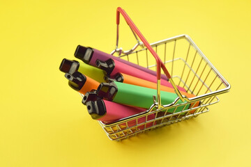 Set of multicolor disposable electronic cigarettes on yellow background.