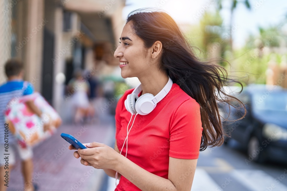 Wall mural young hispanic girl smiling confident using smartphone at street