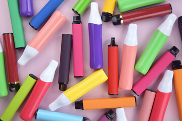 Set of multicolor disposable electronic cigarettes on a pink background.