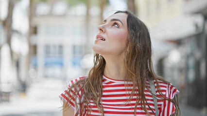 Young blonde woman looking to the sky with relaxed expression at street
