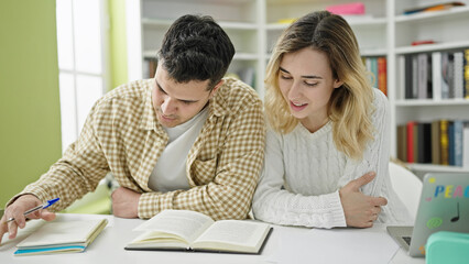 Man and woman students studying together at library university