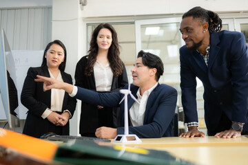 Diverse team of businessmen and engineers consultation on the engineering of a wind turbine that converts wind energy to electricity in the office.