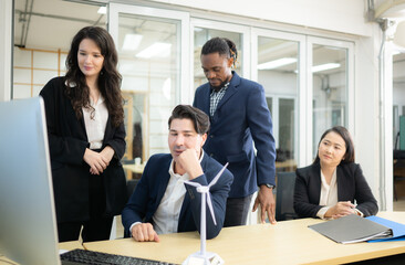 Diverse team of businessmen and engineers consultation on the engineering of a wind turbine that converts wind energy to electricity in the office.