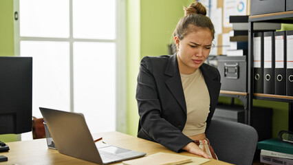 Young beautiful hispanic woman business worker suffering for backache working at office