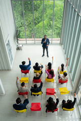 Top view of a group of business people sitting and listening to a presentation in a conference hall