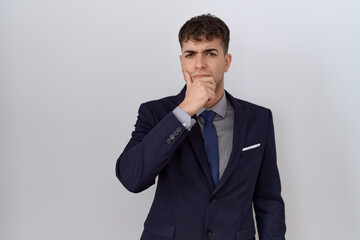 Young hispanic business man wearing suit and tie looking confident at the camera with smile with crossed arms and hand raised on chin. thinking positive.