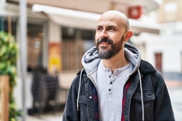Young bald man smiling confident looking to the side at street