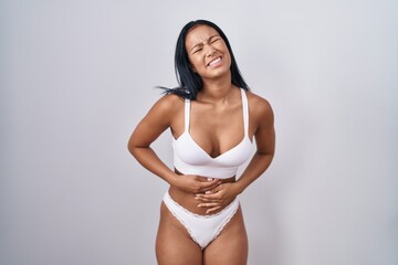 Fototapeta premium Hispanic woman wearing lingerie with hand on stomach because indigestion, painful illness feeling unwell. ache concept.
