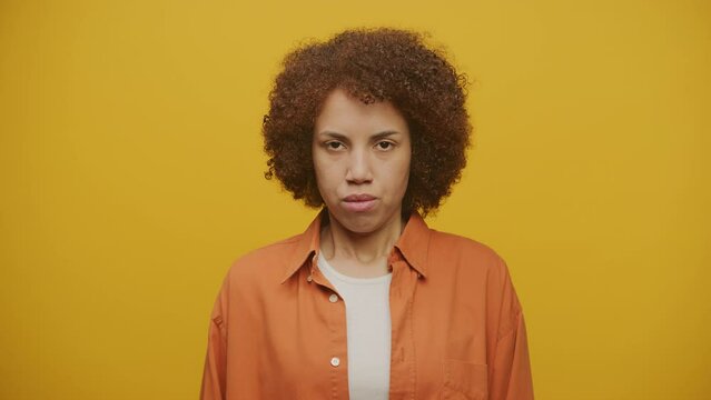 Displeased Female Looking At Camera on Yellow Background
