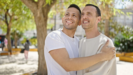 Obraz premium Two men couple smiling confident hugging each other at park
