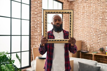 African american man putting face in empty frame looking at the camera blowing a kiss being lovely...