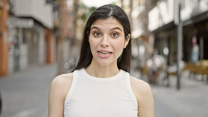Young beautiful hispanic woman speaking at street