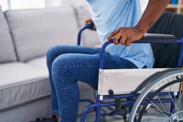 Obraz premium Young latin man sitting on wheelchair at home