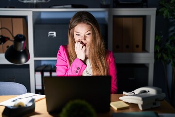 Young caucasian woman working at the office at night looking stressed and nervous with hands on...