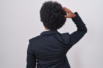 Beautiful african woman with curly hair wearing business jacket and glasses backwards thinking about doubt with hand on head