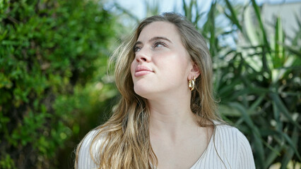 Naklejka premium Young blonde woman smiling confident looking to the sky at park