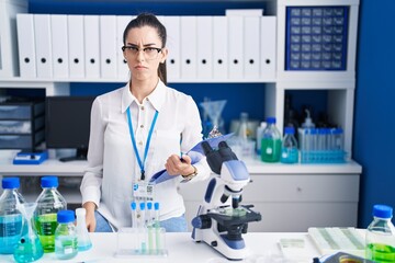Young brunette woman working at scientist laboratory skeptic and nervous, frowning upset because of problem. negative person.