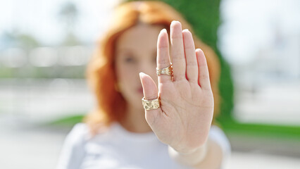 Young redhead woman doing stop gesture with hand at street