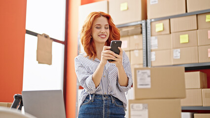 Young redhead woman ecommerce business worker using smartphone smiling at office