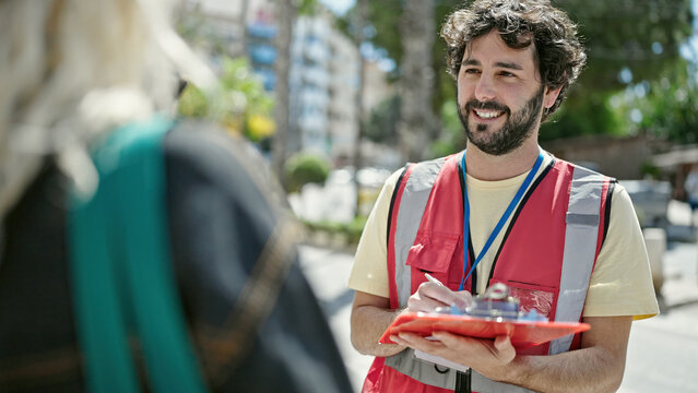 Young Hispanic Man Having Survey Interview Writing On Clipboard At Street