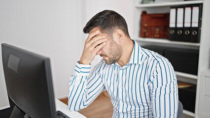 Young hispanic man business worker stressed using computer at office