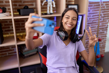 Young african american woman streamer smiling confident make selfie by smartphone at gaming room