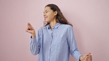 Young beautiful hispanic woman smiling and dancing over isolated pink background