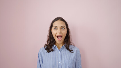 Young beautiful hispanic woman standing with surprise expression over isolated pink background