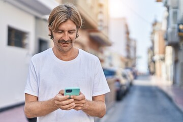 Young blond man smiling confident using smartphone at park