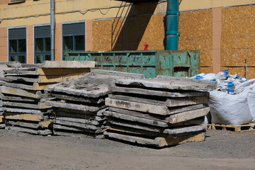 Dismantled concrete slabs and bags of construction waste near the building. Construction site