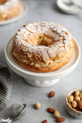 Round-shaped classic French dessert Paris Brest with almonds and hazelnuts on a white plate