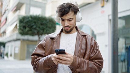 Young arab man listening to music with relaxed expression at street