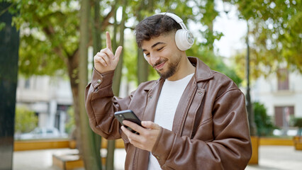 Fototapeta premium Young arab man smiling confident listening to music and dancing at park