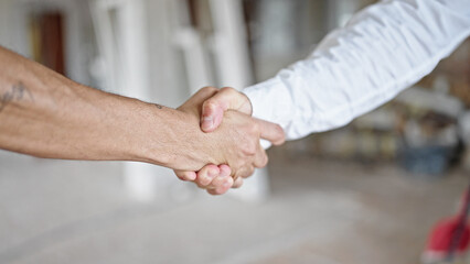 Two men shake hands at construction site