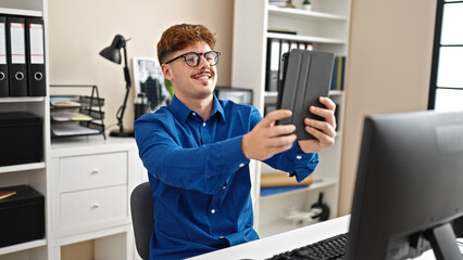 Young hispanic man business worker make selfie by touchpad smiling at the office
