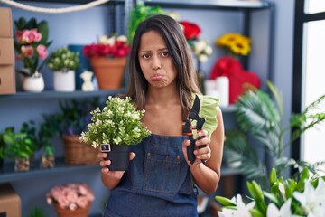 Hispanic young woman working at florist shop depressed and worry for distress, crying angry and afraid. sad expression.