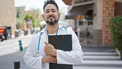 Young latin man doctor smiling confident holding medical report at coffee shop terrace