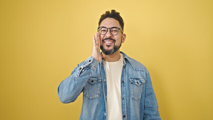 Young latin man smiling confident standing over isolated yellow background