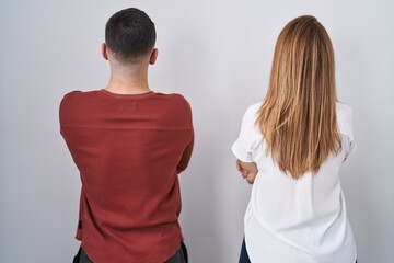 Mother and son standing together over isolated background standing backwards looking away with crossed arms