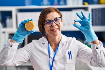 Middle age hispanic woman working at scientist laboratory making vitamin smiling with a happy and cool smile on face. showing teeth.
