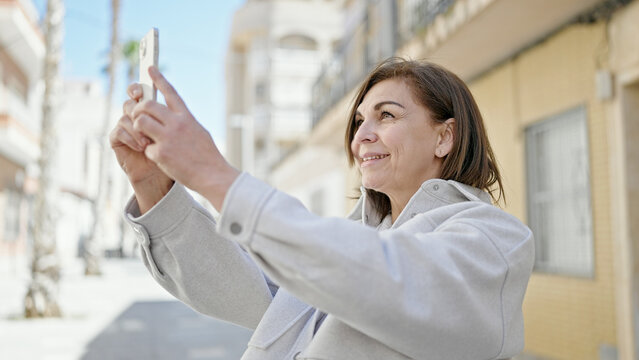 Middle age hispanic woman smiling confident make photo with smartphone at street