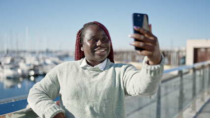 African woman with braided hair taking selfie picture with smartphone at seaside