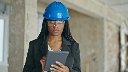 African american woman architect using touchpad thinking at construction site