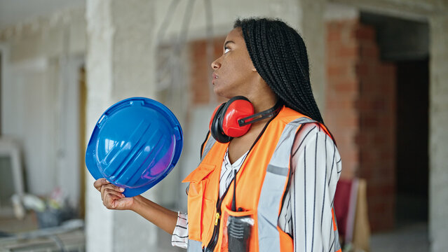 African american woman builder sweating using hardhat as a handfan at construction site