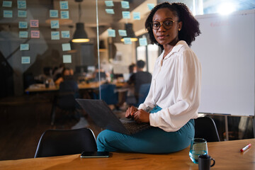 Black businesswoman working on laptop. Portrait of beautiful businesswoman sitting on the desk.