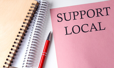 SUPPORT LOCAL word on the pink paper with office tools on white background