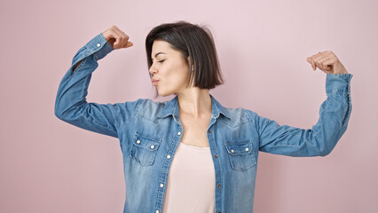 Young caucasian woman kissing arm doing strong gesture with arms over isolated pink background