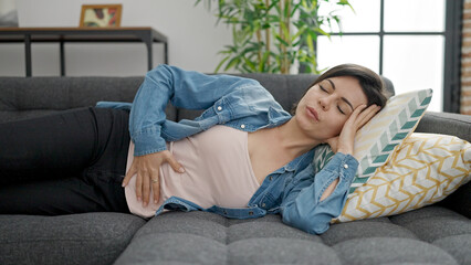 Fototapeta premium Young caucasian woman suffering for stomach ache lying on sofa at home