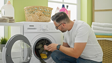 Grey-haired man washing clothes at laundry room