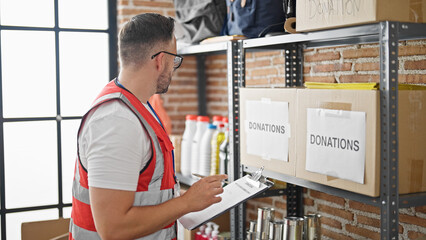 Grey-haired man volunteer writing on checklist at charity center